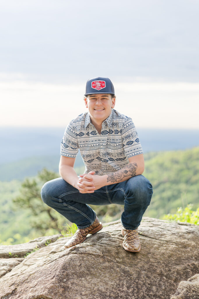 High school senior posing on a rock at sunrise with mountain views in Shenandoah National Park